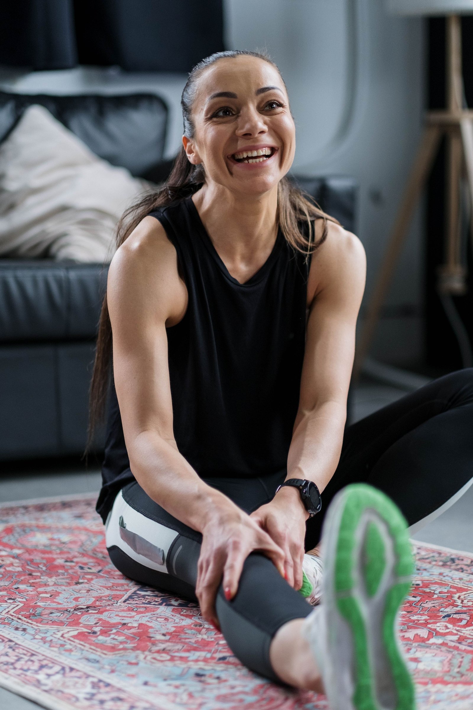 A woman in a training tank stretching and laughing at home